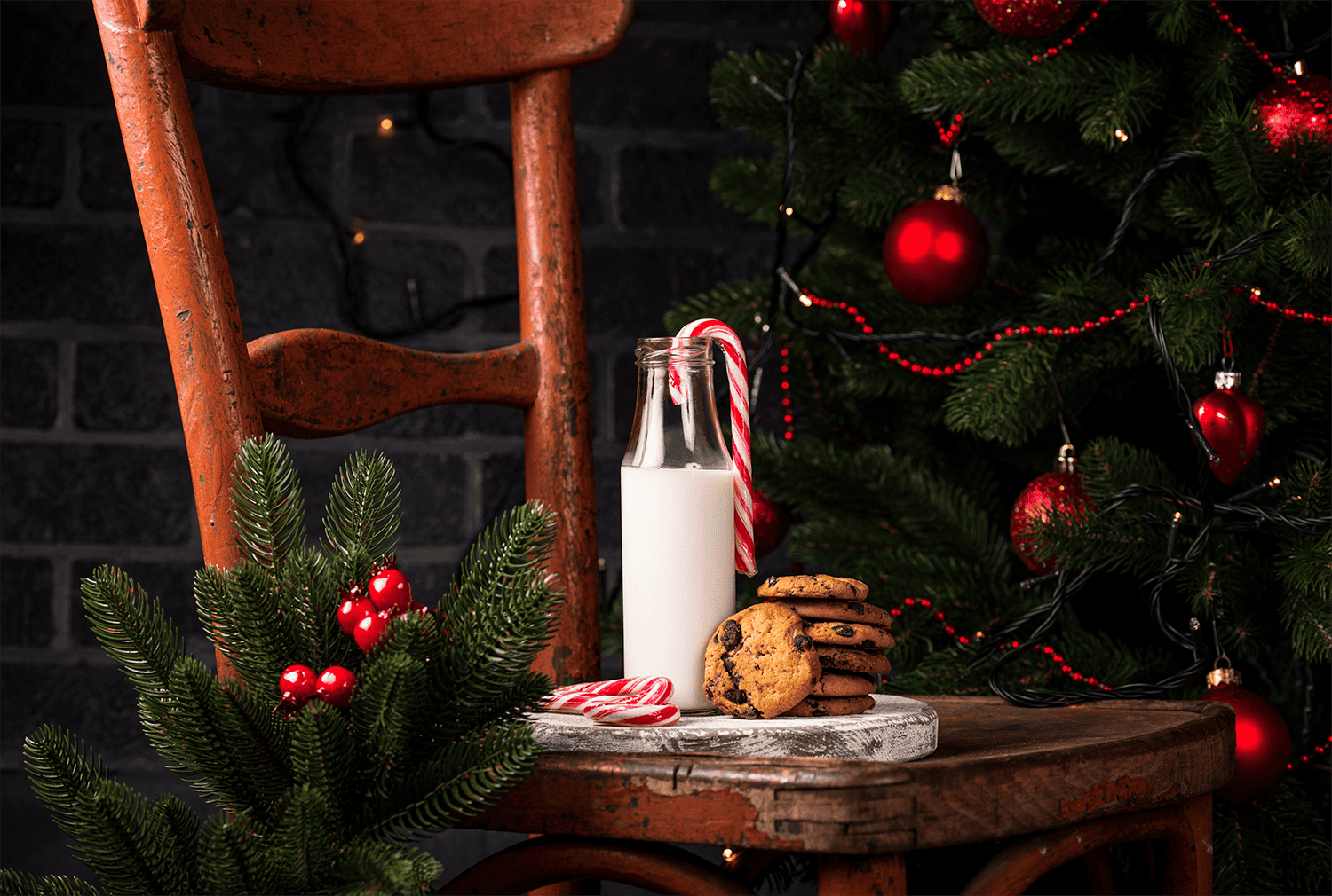 chocolate chip cookies with a candy cane and class of milk on wooden chair